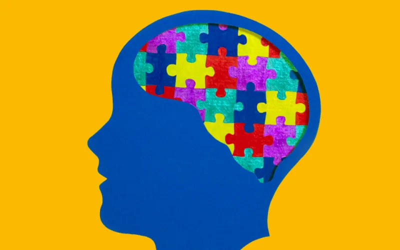 Side profile of a head with multi-coloured jigsaw pieces making up the brain illustrating neurodiversity