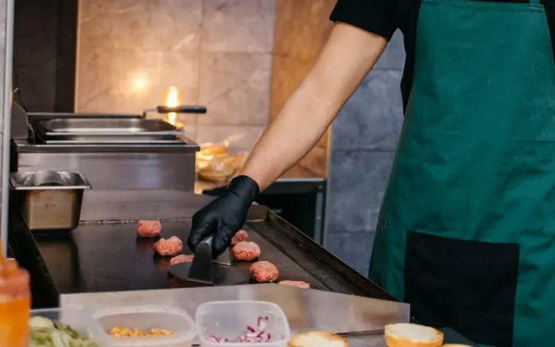 Person cooking burgers in a fast food restaurant