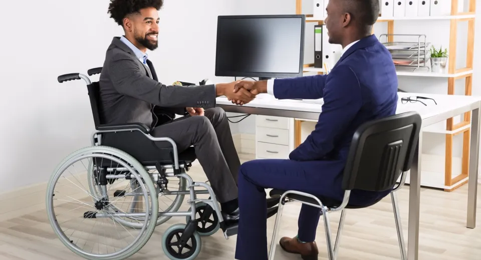wheelchair user shaking hands at desk